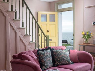 A living room with a staircase and yellow door at Astondene, East Cliff, Southwold
