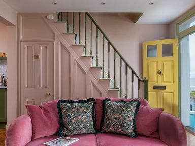 A living room with a pink sofa and yellow door at Astondene, East Cliff in Southwold