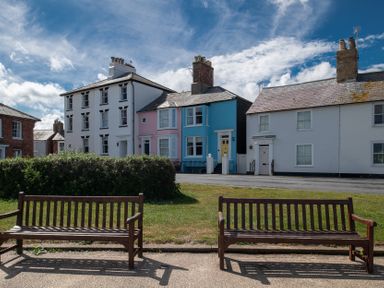 Houses with colorful exteriors and benches in front at Astondene, East Cliff in Southwold