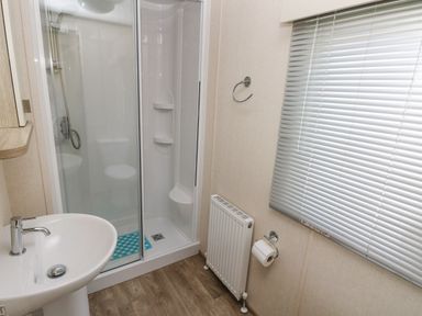 A bathroom with a shower enclosure sink radiator toilet paper holder and window blinds at 116 Woodpecker Lodge in Gilfachrheda near Llanarth