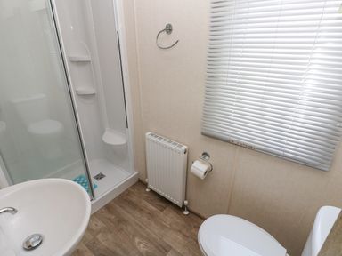 A bathroom with a shower enclosure sink toilet radiator and window with blinds at 116 Woodpecker Lodge in Gilfachrheda near Llanarth