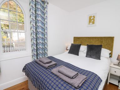 A bedroom with a bed covered by a blue patterned blanket and two gray towels on top at Upper Vestry in Llangrannog