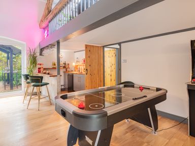 A game room with an air hockey table a bar area with stools and bottles and a wooden door at The Waterfall Retreat in Orton