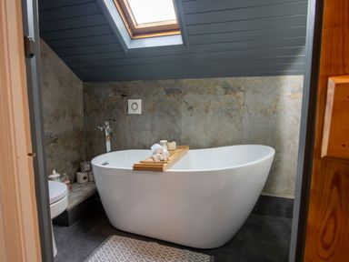 A bathroom with a freestanding bathtub under a skylight at The Waterfall Retreat in Orton