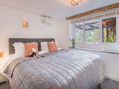 A bedroom with a large bed gray quilt pillows and a window with a plant on the sill at The Waterfall Retreat in Orton