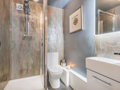 A bathroom with a shower enclosure toilet and sink with a mirror at The Waterfall Retreat in Orton