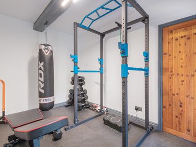 A home gym with a punching bag dumbbells a weight bench a pull-up bar and a wooden door at The Waterfall Retreat in Orton