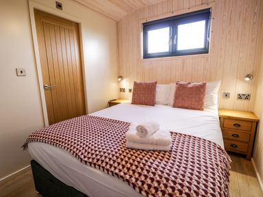A bedroom with a double bed two wooden bedside tables and a window at Betsi Lodge 1 in Llanelidan near Corwen