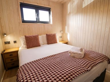 A bedroom with a double bed two side tables and a window at Betsi Lodge 1 in Llanelidan near Corwen