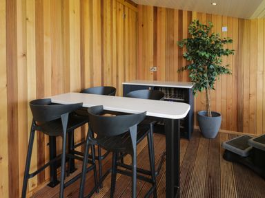 A dining area with a white table and black chairs next to a cabinet and a potted plant at Betsi Lodge 1 in Llanelidan near Corwen