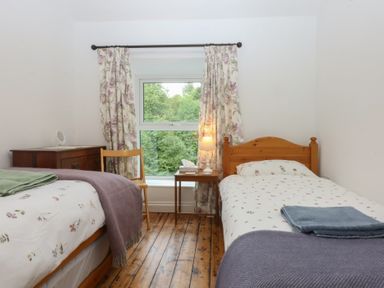 A bedroom with two beds, a window, and a wooden table at Chandos in Dolwyddelan
