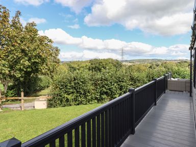 A balcony with black railing overlooking trees and hills at Hazel Lodge in Teigngrace near Newton Abbot