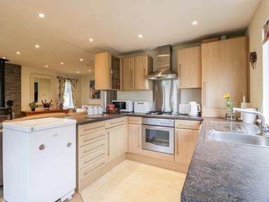 A kitchen with wooden cabinets a white fridge an oven and a sink at Eden Lodge Castlewigg near Whithorn