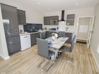 A kitchen with grey cabinets a dining table set with four chairs and place settings at Southend in Welland