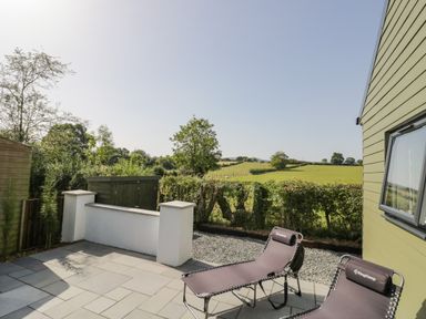 An outdoor patio area with two lounge chairs and a view of green fields at Southend in Welland