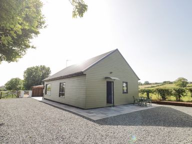 A single story house with a sloped roof and a small patio area with table and chairs surrounded by gravel and greenery at Southend in Welland