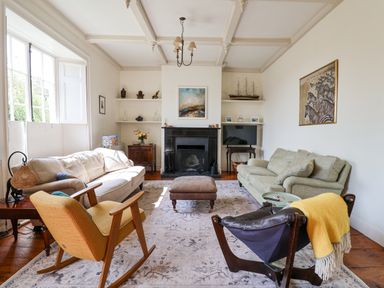 A living room with two sofas a yellow rocking chair a black leather chair a fireplace and a television at Charmouth Lodge in Charmouth