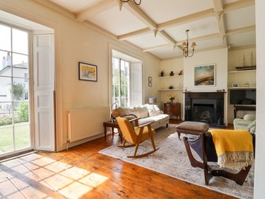 A living room with wooden floor a white sofa rocking chair and fireplace at Charmouth Lodge in Charmouth