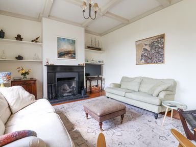 A living room with two sofas a fireplace a coffee table and shelves with decorations at Charmouth Lodge in Charmouth
