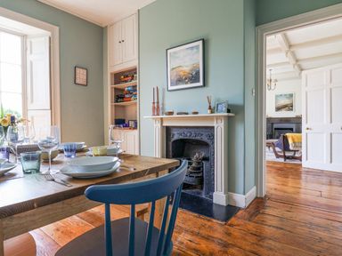 A dining room with a set table a fireplace and shelves with board games at Charmouth Lodge in Charmouth
