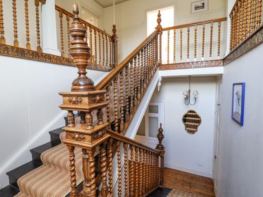 A staircase with carved wooden balusters and a striped carpet runner at Charmouth Lodge in Charmouth