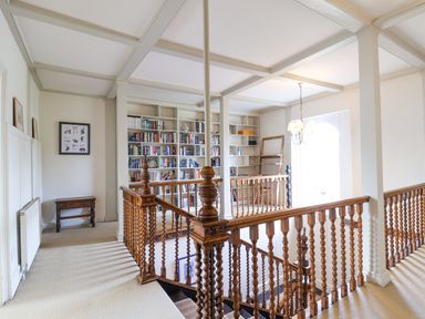 A hallway with wooden spiral staircase and built in bookshelves at Charmouth Lodge in Charmouth