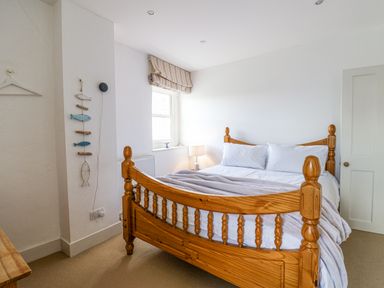 A bedroom with a wooden bed and striped window blind at Charmouth Lodge in Charmouth