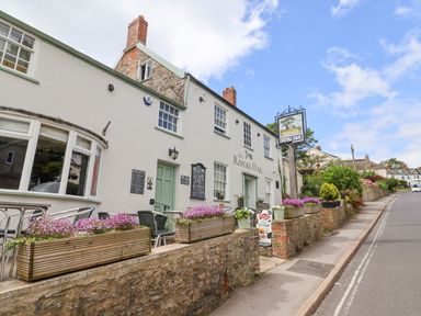 Exterior of The Royal Oak pub with outdoor seating and flower boxes on a street in Charmouth