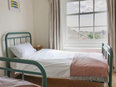 A bedroom with a single bed a window with curtains and a bedside table at Charmouth Lodge in Charmouth