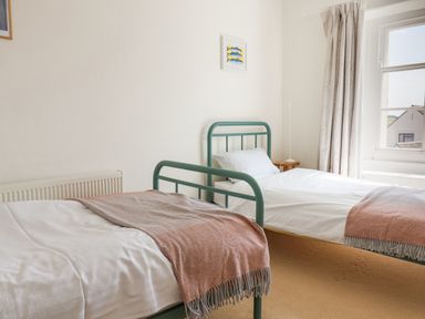 A bedroom with two single beds with green metal frames each with white bedding and brown throws at Charmouth Lodge in Charmouth