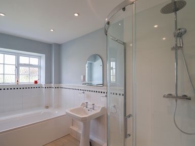 A bathroom with a bathtub sink shower and a window at Charmouth Lodge in Charmouth