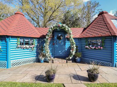 A blue cottage with a decorated door and roof at Applejacks Orchard in Holywell
