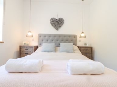 A bedroom with a double bed two bedside tables and hanging lamps at Higher Bolenna in Perranporth