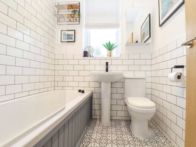 A bathroom with a bathtub a pedestal sink a toilet and patterned floor tiles at Higher Bolenna in Perranporth