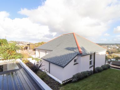 An exterior view of a house with a tiled roof a garden and plants at Higher Bolenna in Perranporth