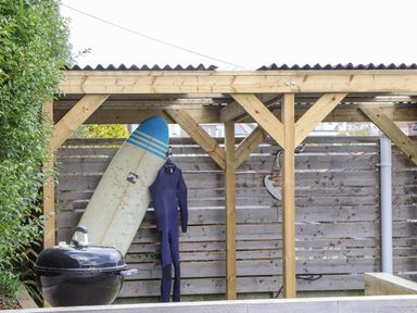 A covered outdoor area with a surfboard wetsuit and barbecue grill at Higher Bolenna in Perranporth