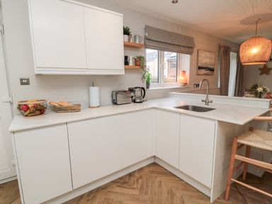 A kitchen with white cabinets countertop sink toaster kettle and fruit baskets at Driftwood Sands in Beadnell