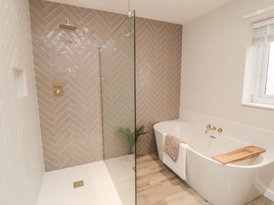 A bathroom with a walk-in shower and a bathtub at Driftwood Sands in Beadnell