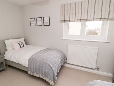 A bedroom with a single bed beside a window with a radiator below it at Driftwood Sands in Beadnell