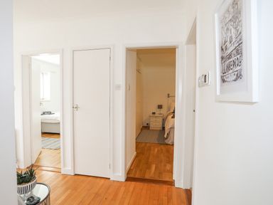 A hallway with wooden floors leading to a bedroom and another room at Ty Cerrig in Llanbedrog