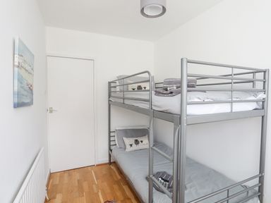 A small bedroom with a metal bunk bed and wooden floor at Ty Cerrig in Llanbedrog