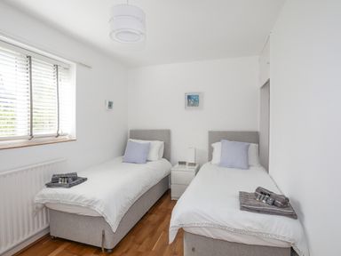 A bedroom with two single beds a window and a nightstand at Ty Cerrig in Llanbedrog