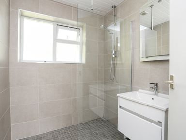 A bathroom with a walk-in shower and a sink with a mirror cabinet at Ty Cerrig in Llanbedrog