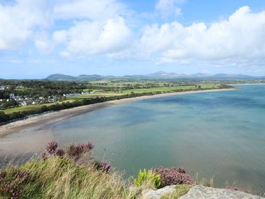 A coastal landscape with a sandy beach green fields and houses at Ty Cerrig in Llanbedrog
