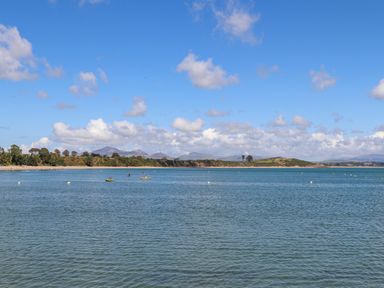 A bay with boats on water and a distant shoreline with hills under a blue sky at Ty Cerrig in Llanbedrog