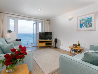 A living room with sofas a television and a view of the sea at Wavetop in Carbis Bay