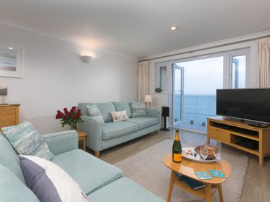 A living room with sofas a coffee table and a television with a view of the sea at Wavetop in Carbis Bay