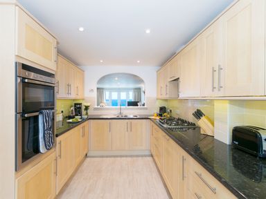 A kitchen with light wood cabinets black countertops a double oven and a gas stove at Wavetop in Carbis Bay