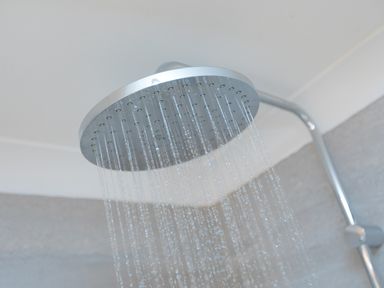 A shower head with water flowing in a bathroom at Wavetop in Carbis Bay