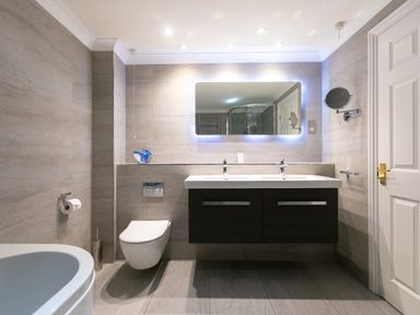 A bathroom with double sink vanity mirror toilet and shower at Wavetop in Carbis Bay